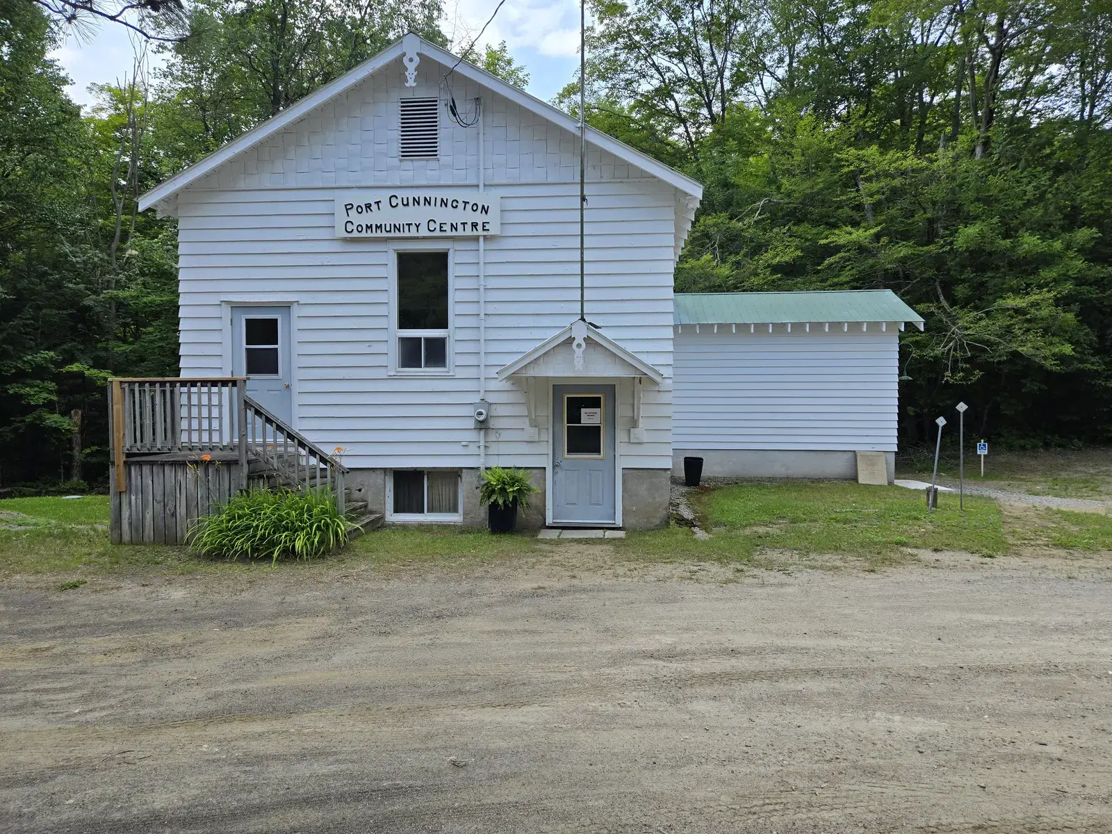 The front of the community centre, white clapboard with a small covered porch and a wooden ramp.